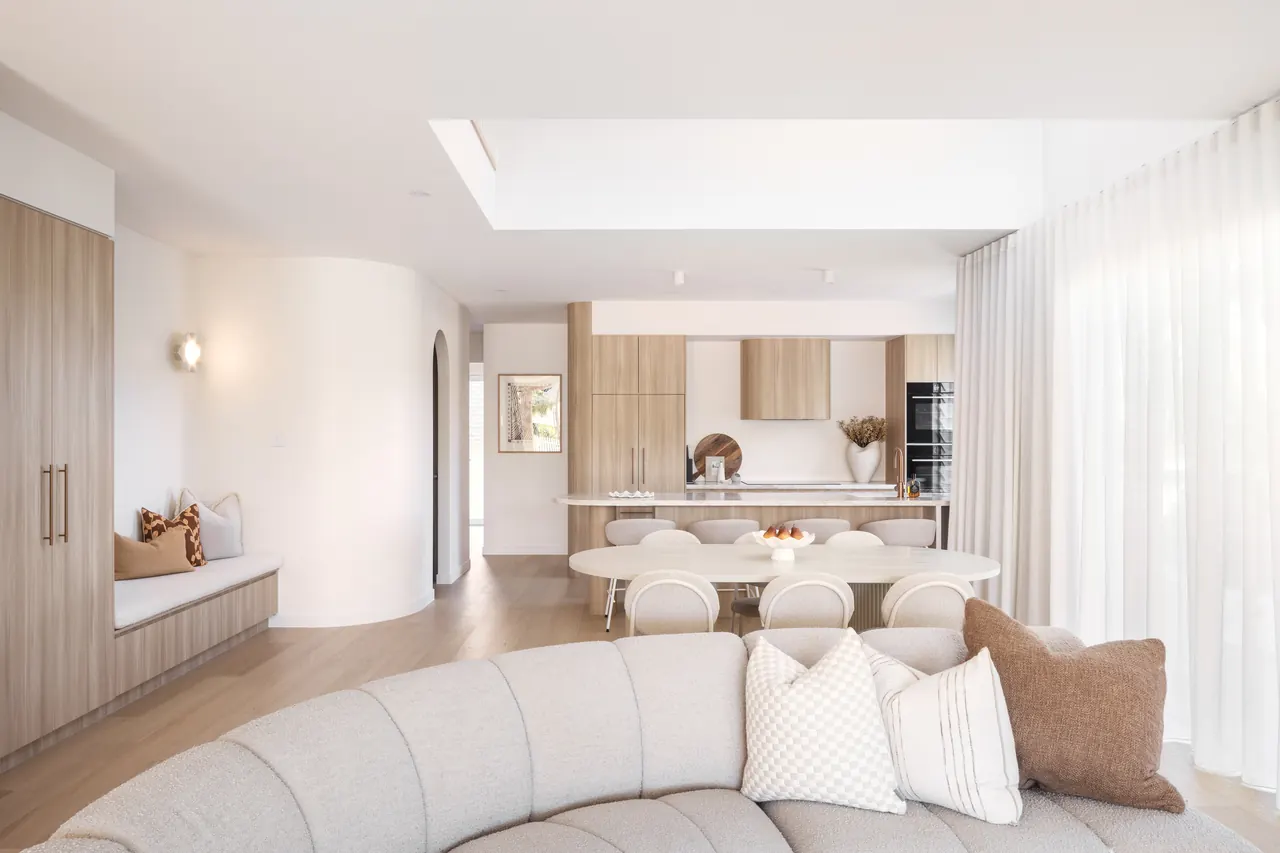 Open-plan living with a curved modular sofa and kitchen beyond