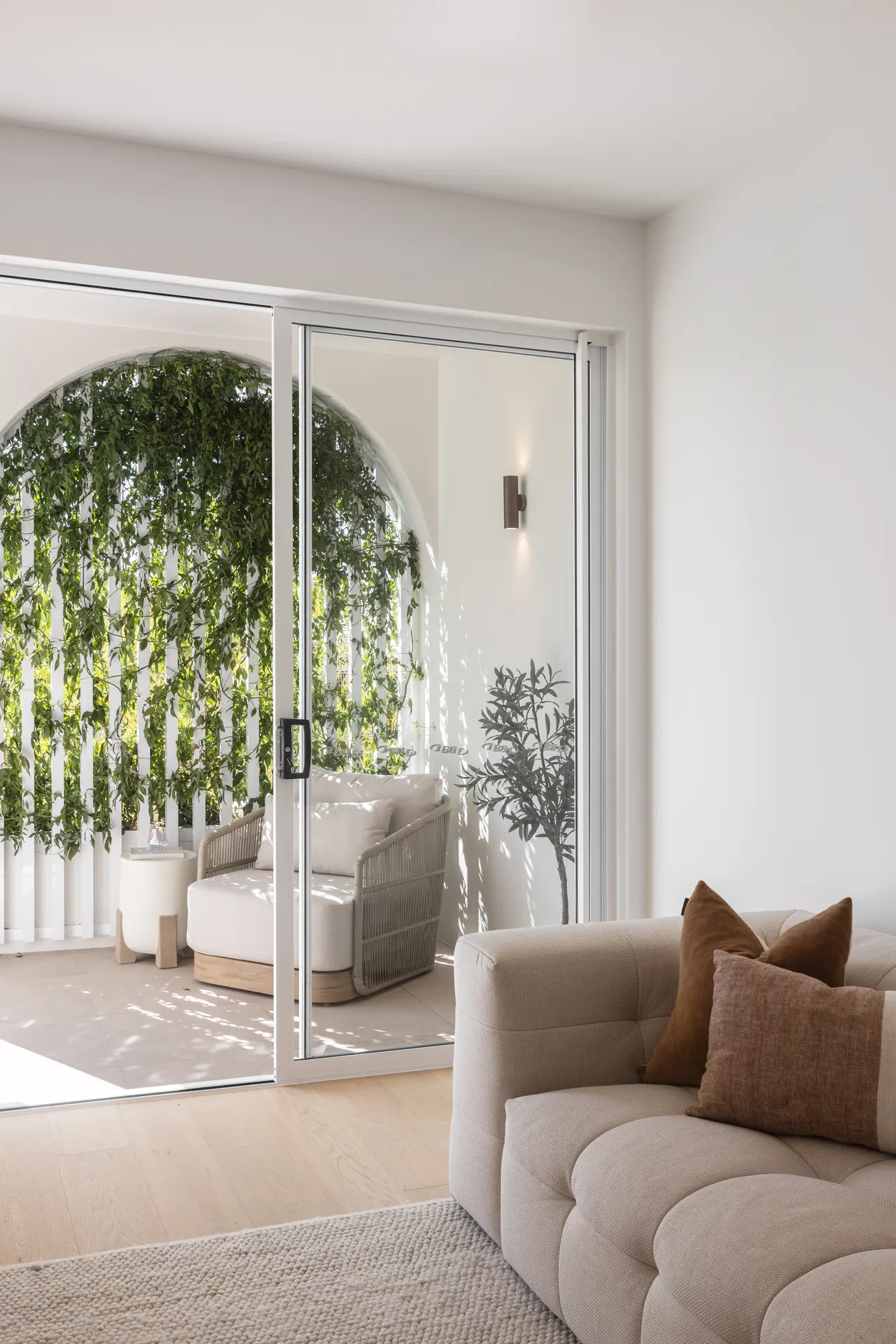 Living room opening to a leafy arched terrace
